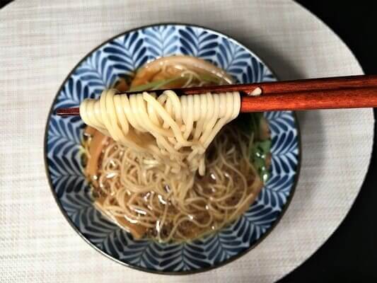 飯田商店醤油らぁ麺の麺を箸でつまんでアップでみせている
